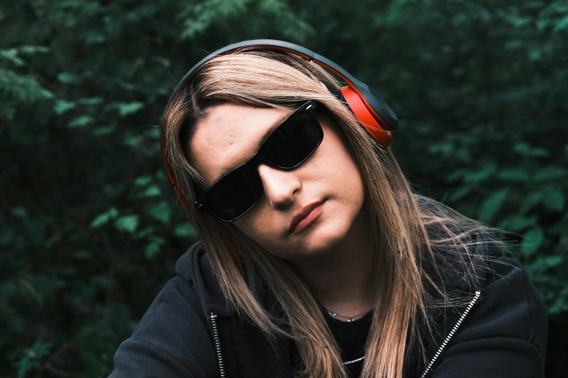 Kobieta w okularach słonecznych słucha muzyki w zielonym parku