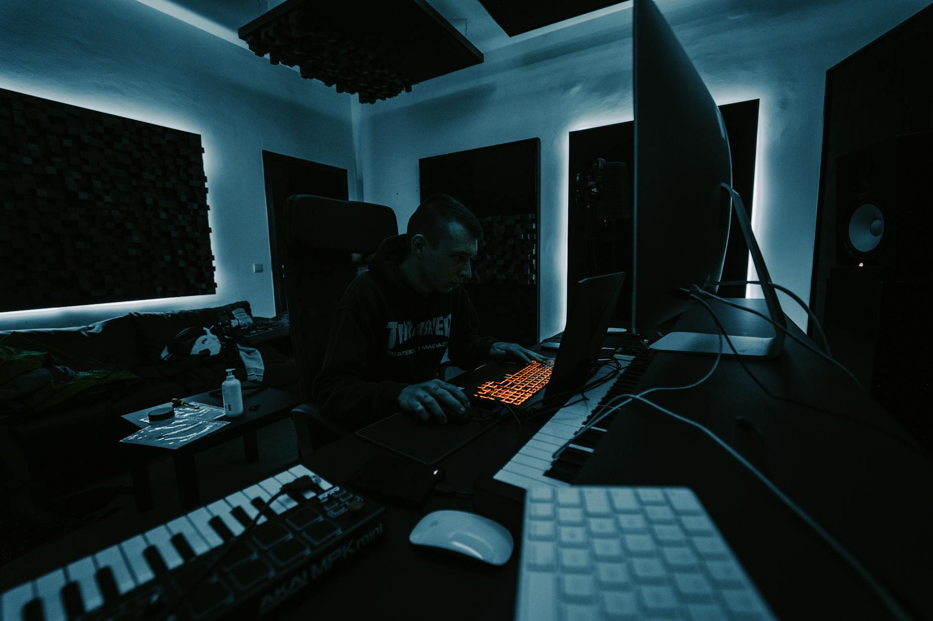 Producent muzyczny pracuje przy komputerze w ciemnym, nowoczesnym studiu
