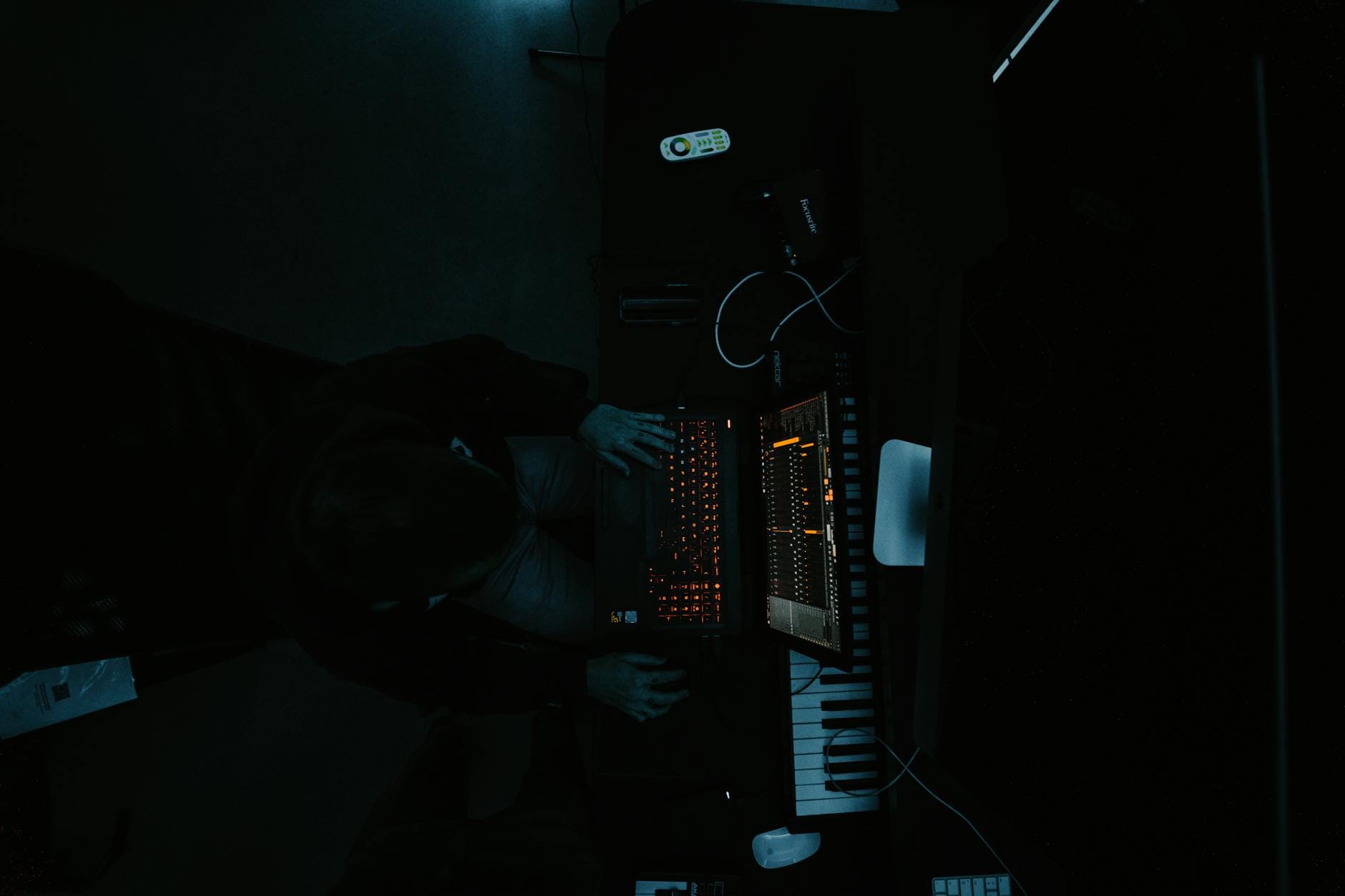 Producent muzyczny pracuje przy laptopie w ciemnym studiu ambient