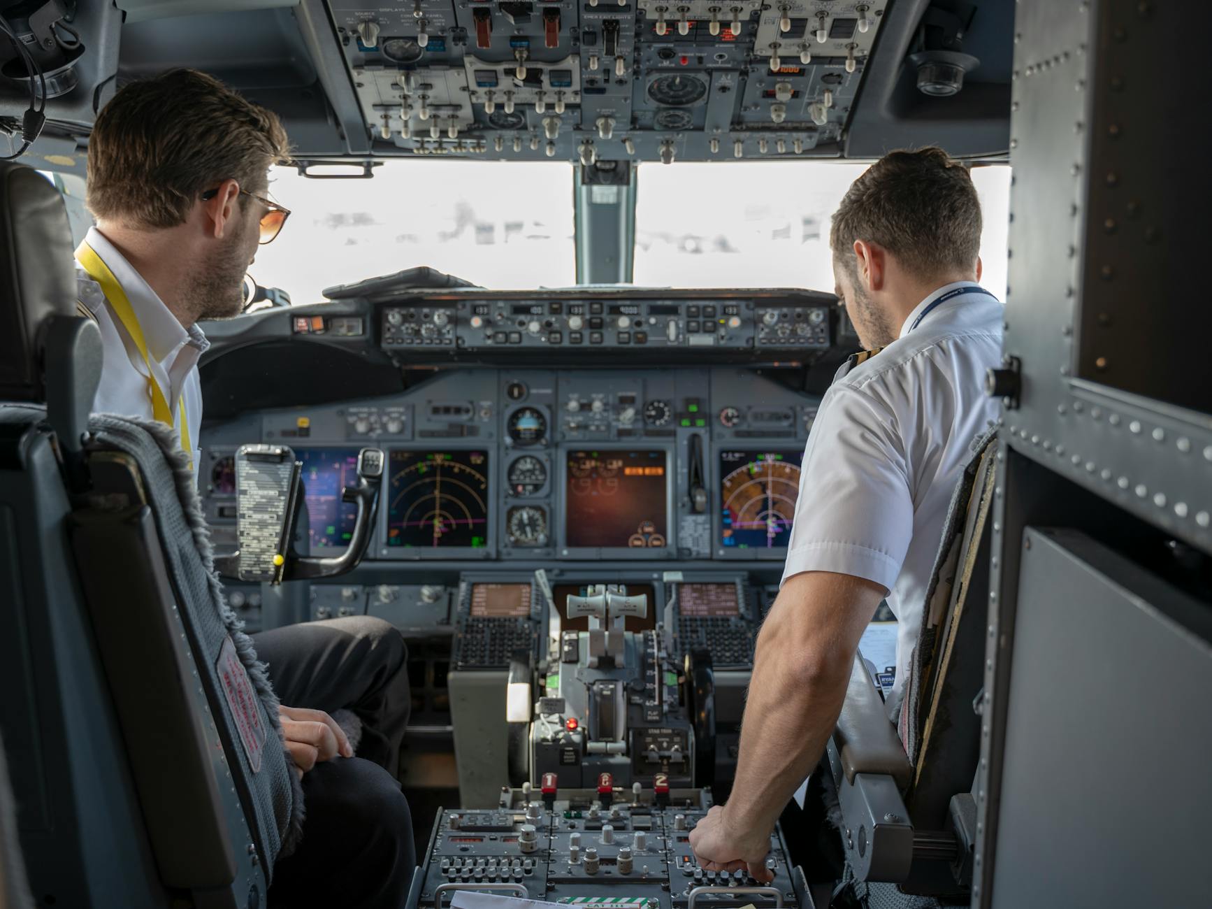 Dwóch pilotów w kokpicie samolotu pasażerskiego przy panelu avioniki
