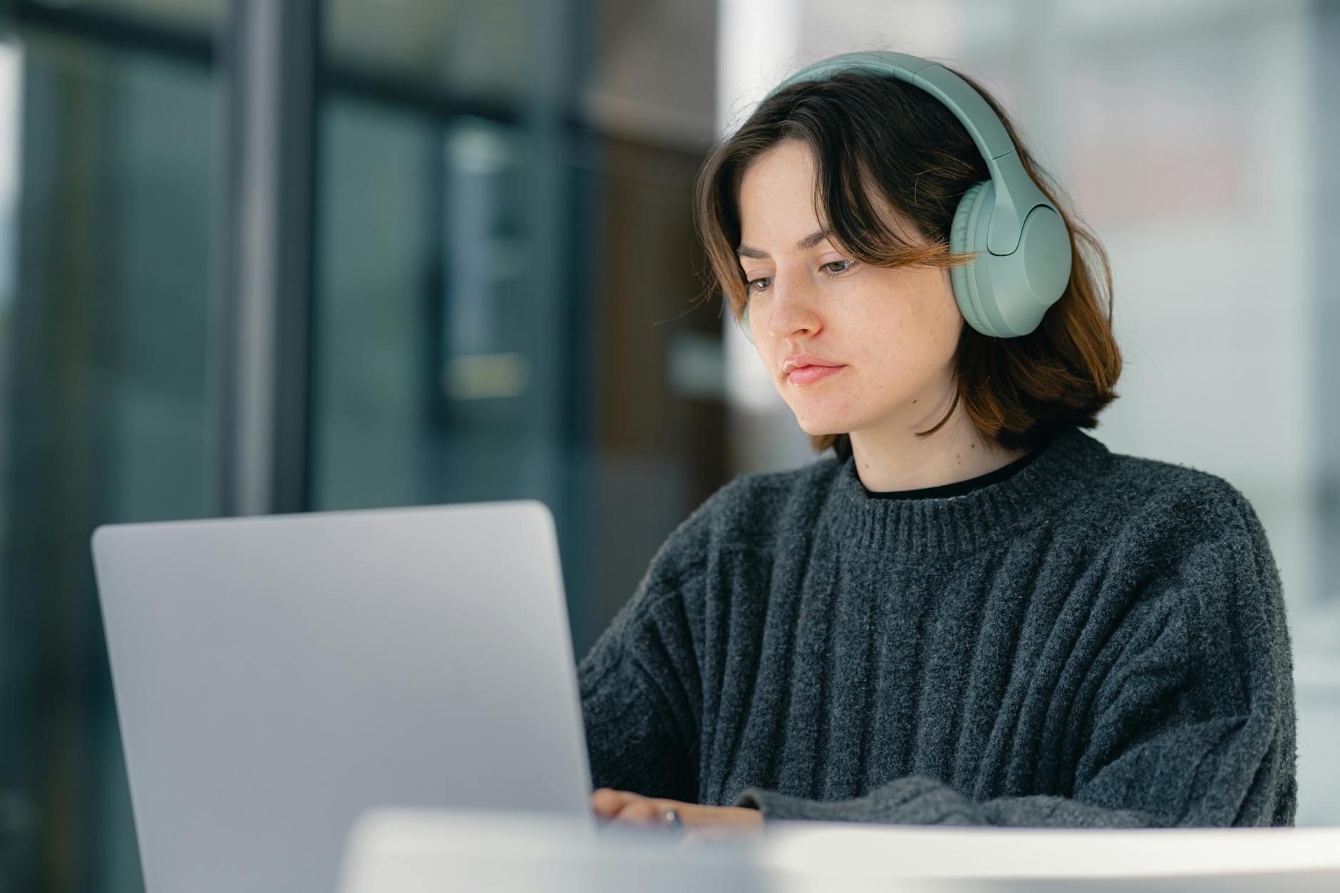 Kobieta w słuchawkach skupiona przy laptopie podczas pracy głębokiej