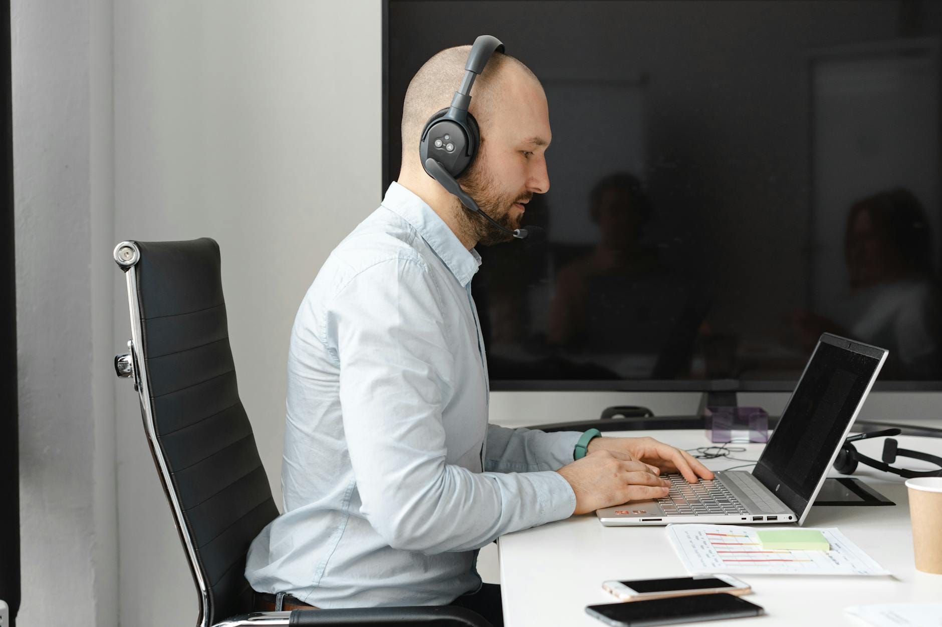 Pracownik call center w słuchawkach przy laptopie w biurze