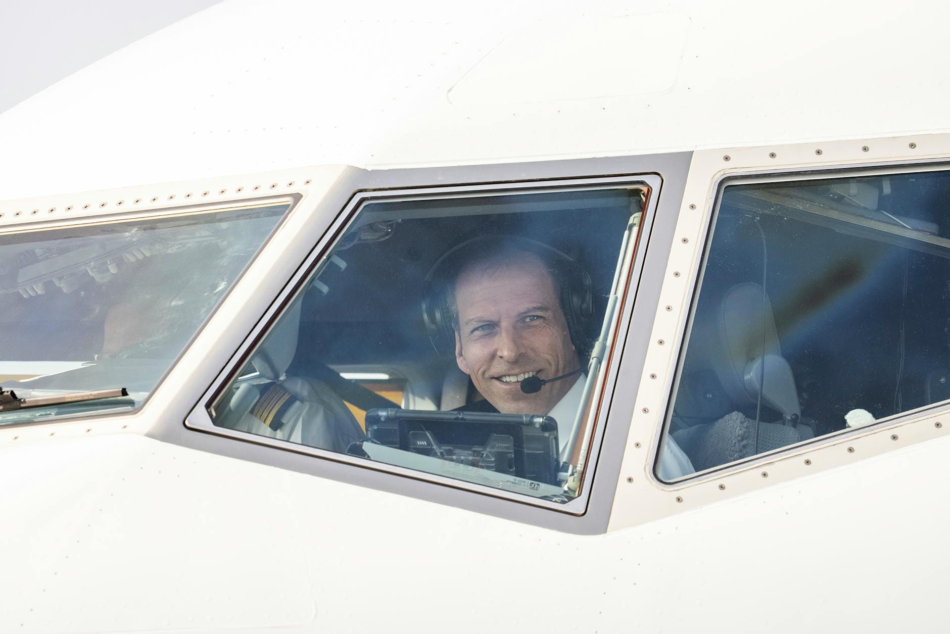 Uśmiechnięty pilot liniowy w kokpicie samolotu pasażerskiego