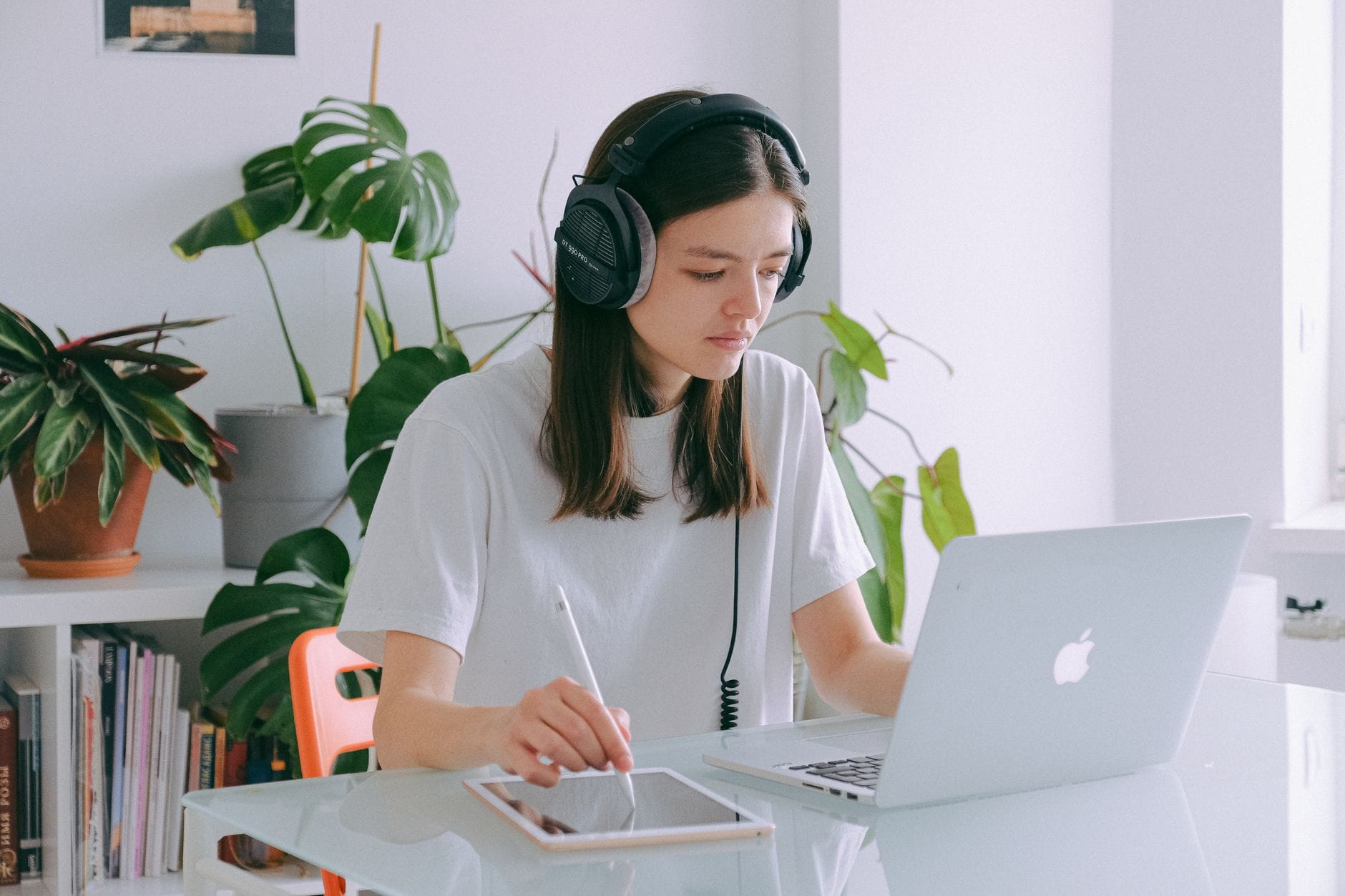 Kobieta w słuchawkach pracuje przy laptopie, słuchając muzyki filmowej